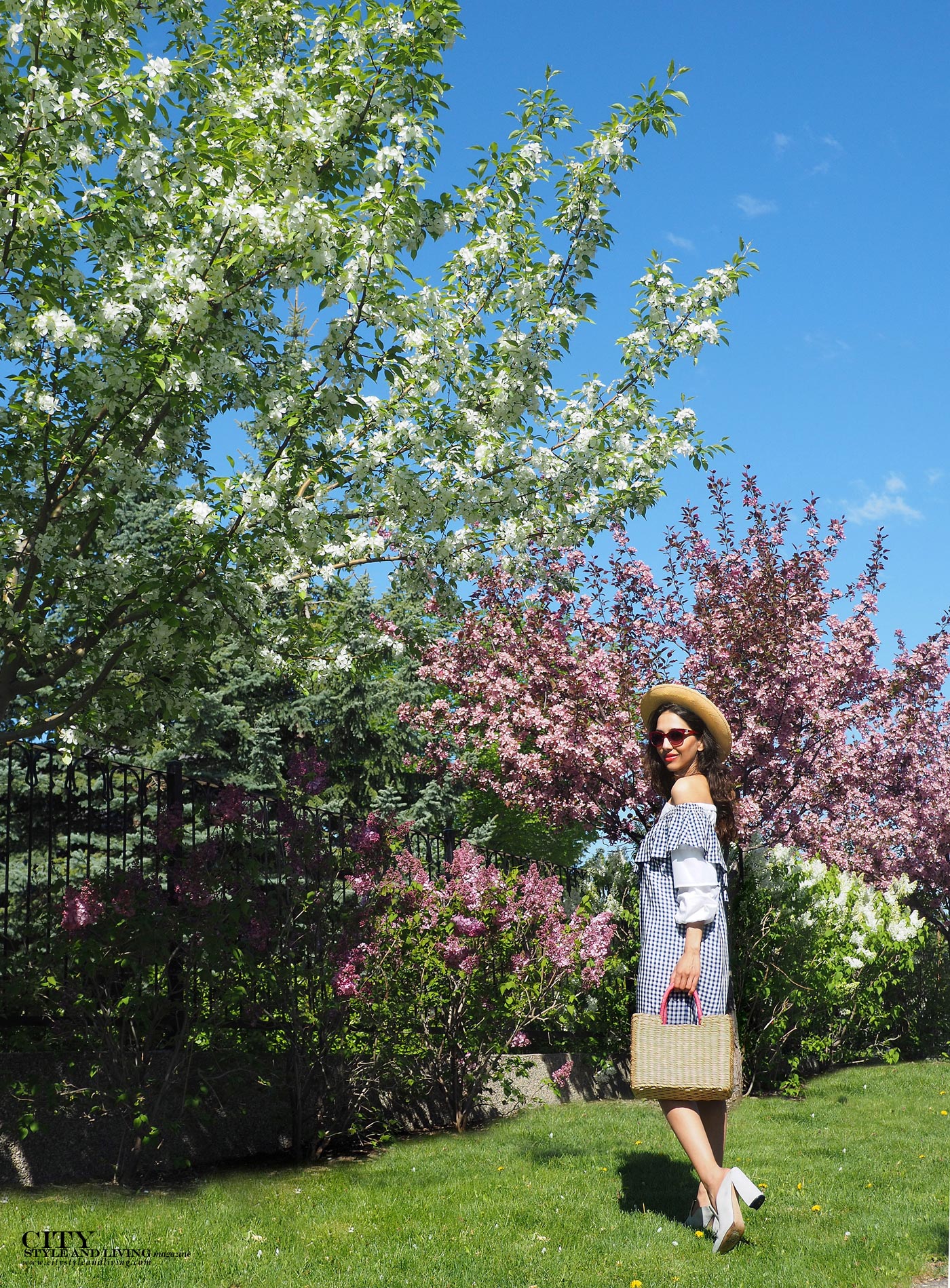 City style and living magazine The Editors Notebook style fashion blogger Shivana Maharaj summer picnic and gingham dress with mules drinking rose walking wearing a straw hat and bag